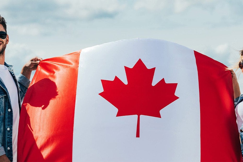 male and female wearing sunglasses holding a canadian flag