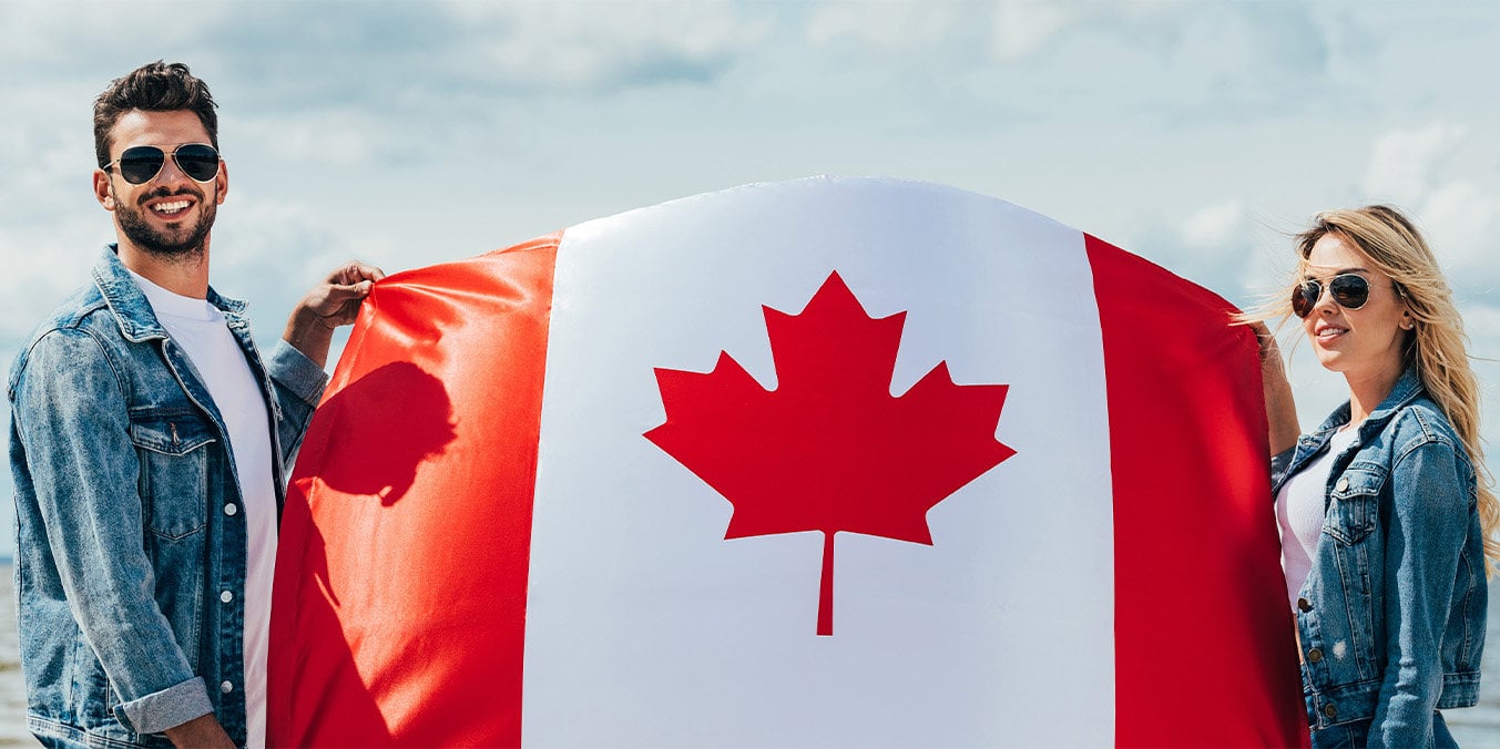 male and female wearing sunglasses holding a canadian flag